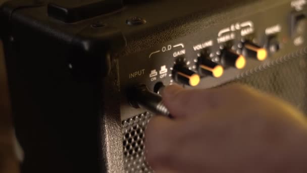 Een gitaarkabel aansluiten op een combo versterker. Close-up. - Video