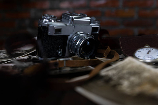Vintage film camera and old photographs on a rustic surface  - Φωτογραφία, εικόνα