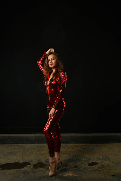 girl in a red suit posing on a black background - Foto, Imagem