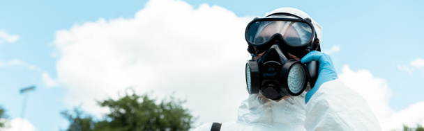 Reinigungsspezialist für Atemschutzmasken, der während der Coronavirus-Pandemie im Park mit dem Handy spricht, panoramische Orientierung - Foto, Bild