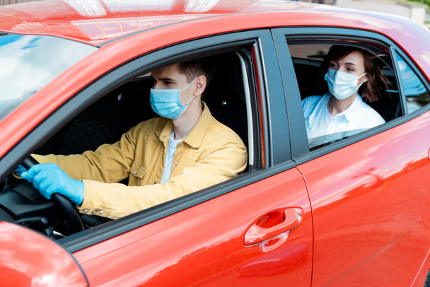 férfi sofőr és nő orvosi maszkban és kesztyűben a taxiban a kovid-19 világjárvány idején - Fotó, kép