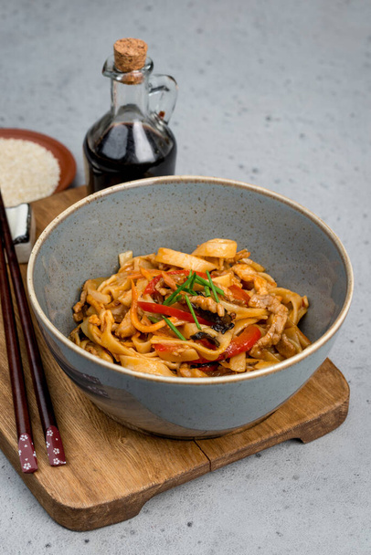 Wheat noodles with meat and vegetables in a deep plate. Close-up shot - Foto, Imagen