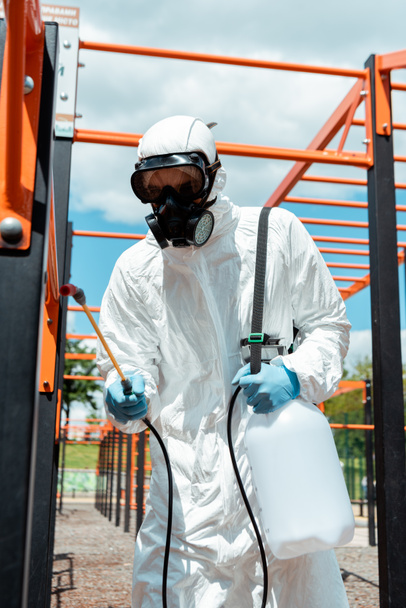 especialista en traje de felpudo y respirador desinfectando campo deportivo en parque durante pandemia de covid-19
 - Foto, imagen