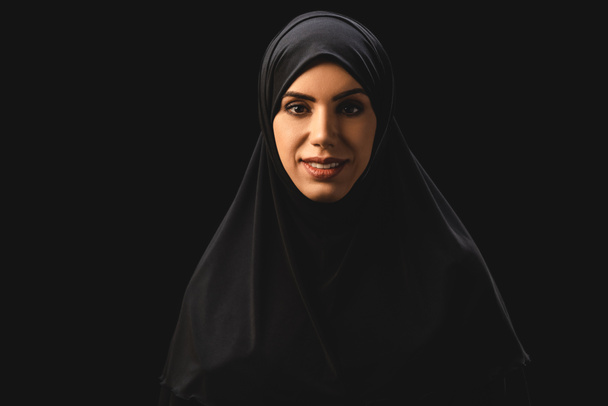 Mulher muçulmana bonita sorrindo para a câmera isolada em preto
  - Foto, Imagem
