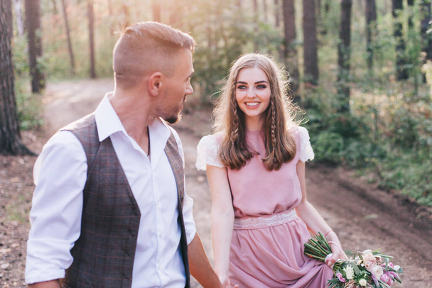 Beautiful couple at the photoshoot of love story in the forest in a rustic dress - Zdjęcie, obraz