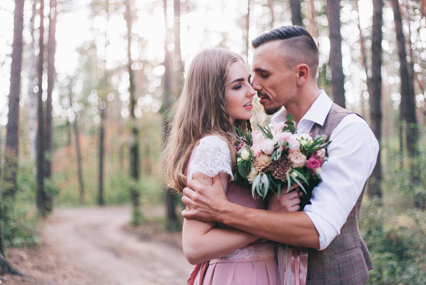 Beautiful couple at the photoshoot of love story in the forest in a rustic dress - Φωτογραφία, εικόνα
