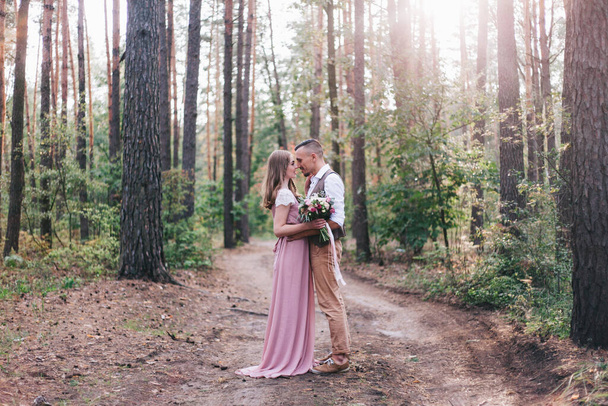 Beautiful couple at the photoshoot of love story in the forest in a rustic dress - Fotografie, Obrázek