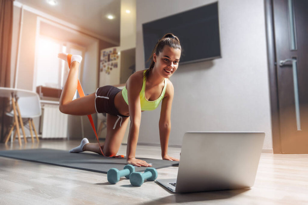 Young caucasian woman exersising with a fitness gum at home via internet. Online training concept. - Fotografie, Obrázek
