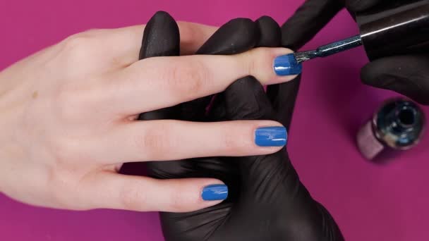 μανικιουρίστα βάφει τα νύχια των πελατών με μπλε βερνίκι νυχιών - Πλάνα, βίντεο