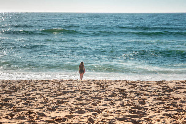 Strand met vrouw in de verte kijkend naar de horizon - Foto, afbeelding