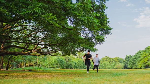 緑の公園で友人と走るスポーツマン - 写真・画像