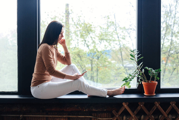 Woman relaxing at home with smart phone indoor - Foto, Imagen