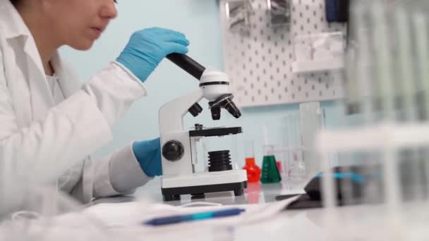 Female medical research scientist looking through microscope. - Felvétel, videó