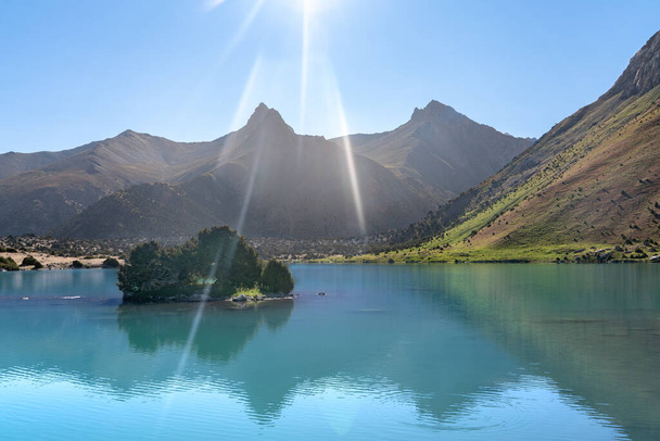 Rozległy widok na Pamir i spokojny kemping nad jeziorem Kulikalon w górach Fann w Tadżykistanie. Gromadzenie kolorowych refleksji w czystym jeziorze lodowym. - Zdjęcie, obraz