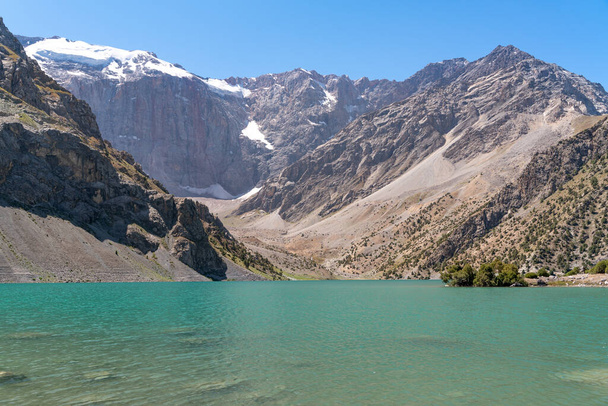 La vista de la cordillera Pamir y el camping tranquilo en el lago Kulikalon en las montañas Fann en Tayikistán. Increíble reflejo colorido en el lago de hielo puro
. - Foto, Imagen