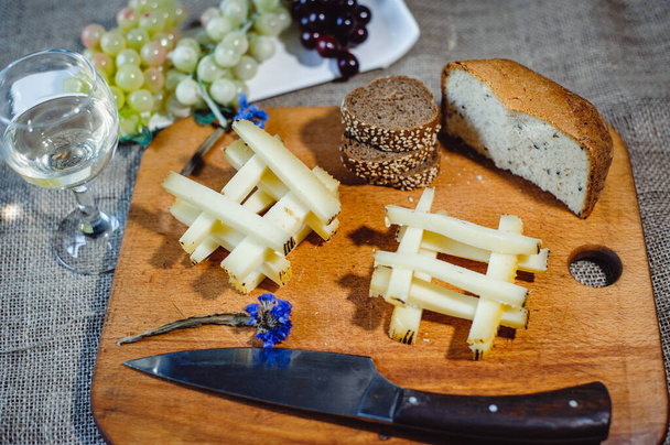 Кусок спелого Графа или Gruyere de Comte, французский сыр AOC из коровьего молока, нарезанный соломинками. Натюрморт из вина и сыра
 - Фото, изображение