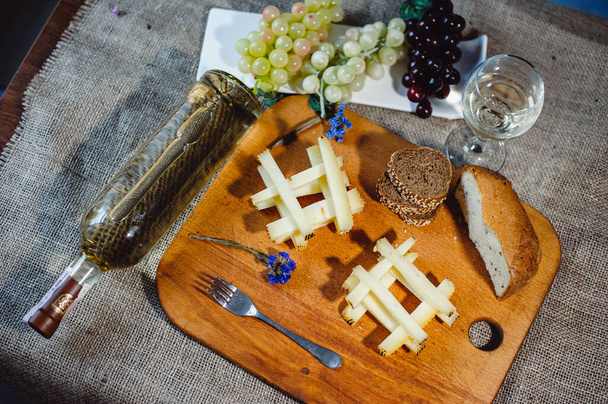 Ένα κομμάτι ώριμου κομήτη ή Gruyere de Comte, γαλλικό τυρί AOC από αγελαδινό γάλα, κομμένο σε φέτες με καλαμάκια. Κρασί και τυρί νεκρές φύσεις. μποφόρ - Φωτογραφία, εικόνα