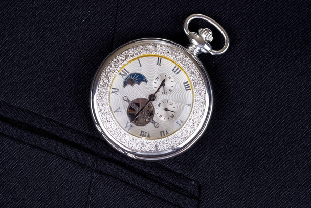 Arka plan kompozisyonu olarak siyah bir iş elbisesinin üzerindeki cep saati - Fotoğraf, Görsel