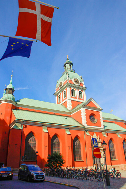 ストックホルム、スウェーデン- 2016年6月22日:スカンディナヴィアの首都ストックホルムの中心部にある観光地区「ガムラ」の通り。北欧の古典建築。スウェーデンと欧州連合の旗. - 写真・画像