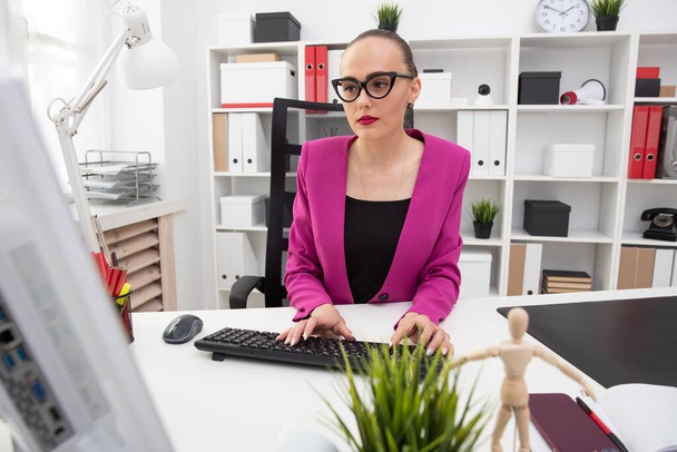 A girl in a business style works at a computer in office - Photo, Image