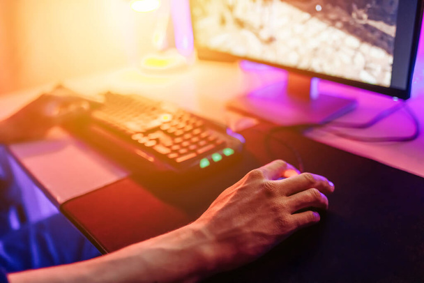Close-up of a gamer's hand on a computer mouse, a person playing video games online - Фото, изображение