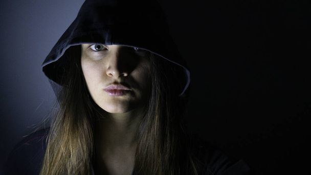 Retrato de una mujer con capucha en la oscuridad
. - Foto, Imagen