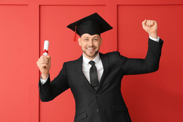 Man in graduation hat and with diploma on color background - Photo, Image