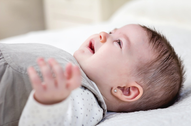 Bebê menina chorando sobre a cama branca
 - Foto, Imagem