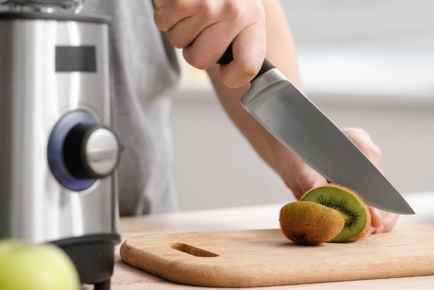 Man cutting fruit for making healthy smoothie at home, closeup - Foto, Imagen