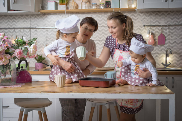 Família mãe, avó e duas irmãs cozinham na cozinha
. - Foto, Imagem