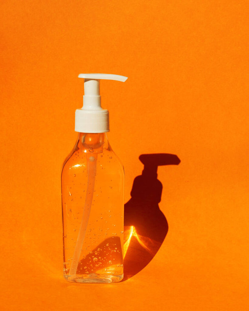 Μπουκάλι με απολυμαντικό χεριών gel. Πορτοκαλί φόντο. Μέσα απολύμανσης του χεριού κατά τη διάρκεια πανδημίας του ιού του κερατοειδούς - Φωτογραφία, εικόνα