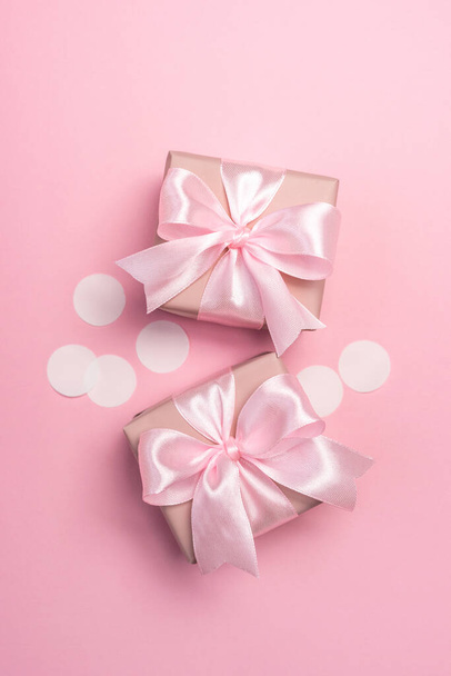 Két ajándék vagy jelen doboz díszített konfetti rózsaszín pasztell háttér. Első látásra. Lapos laikus kompozíció születésnapra vagy esküvőre. Függőleges irány. - Fotó, kép