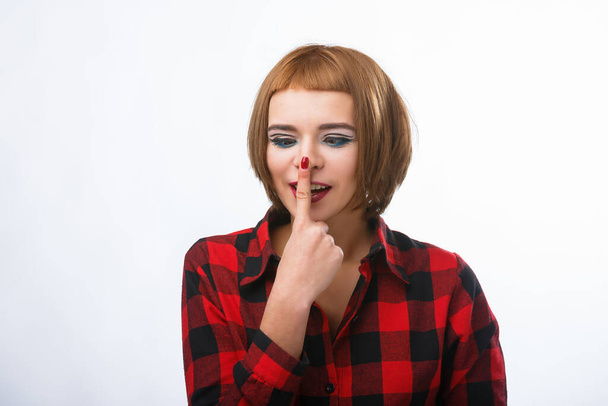 Young casual style woman portrait isolated over white background. Girl touches nose with finger. Red haired lady. - Foto, immagini