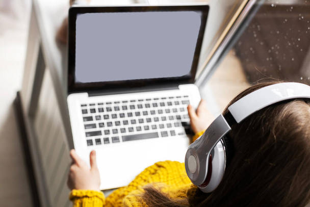 A child with a laptop. Kids distance learning. Focus on headphones. - 写真・画像
