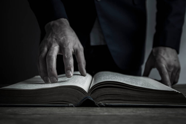 Ο άνθρωπος διαβάζει βιβλίο σε σκούρο φόντο - Φωτογραφία, εικόνα