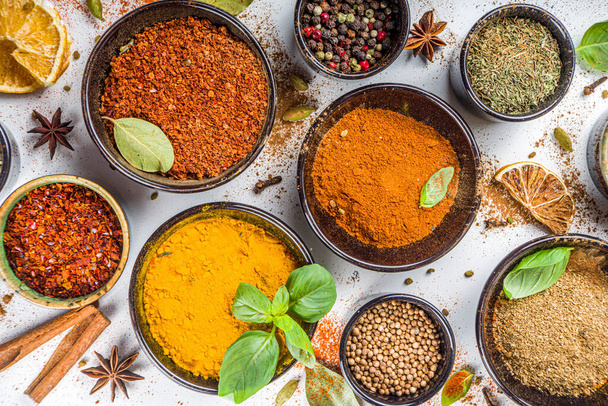 Set of Spices and herbs for cooking. Small bowls with colorful  seasonings and spices - basil, pepper, saffron, salt, paprika, turmeric. On white stone table background top view copy space - Photo, Image