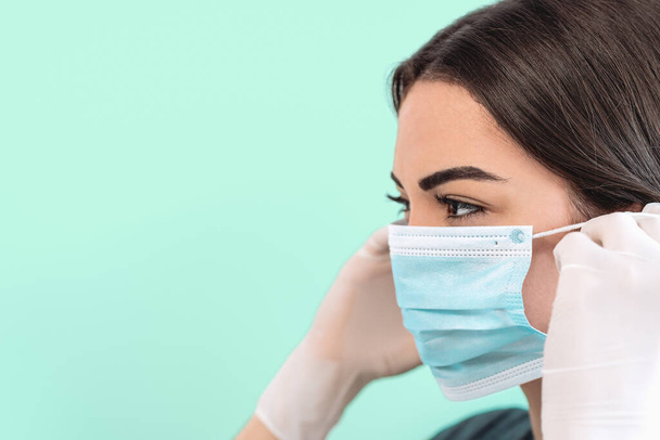 Young woman doctor portrait wearing surgical face mask and gloves - People working for preventing and stop corona virus spreading - Healthcare medicine and coronavirus impact concept - Фото, изображение