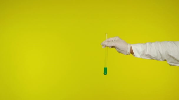 Ruka v latexové rukavici ochrana ukazuje skleněnou trubici se zelenou látkou - Záběry, video