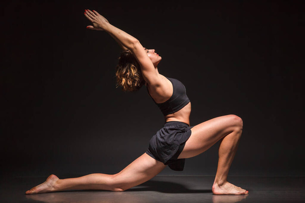 Young girl doing yoga on a black background - Zdjęcie, obraz