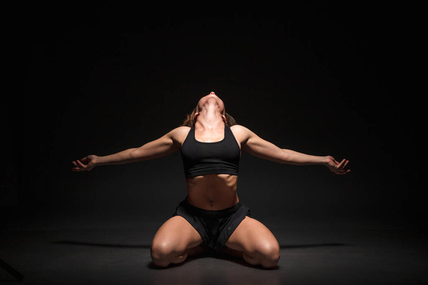 Young girl doing yoga on a black background - Zdjęcie, obraz