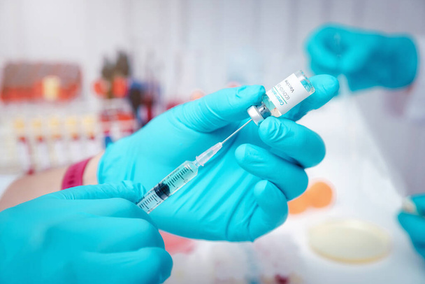 研究者や科学者は実験室で注射器にワクチンをロードする。研究者はCOVID-19ウイルスを治療するワクチンを発明しています. - 写真・画像