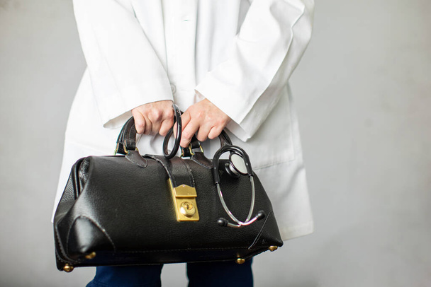 Női orvos kezében egy fekete bőr orvos táskája tart az irodába, hogy gyakorolja az orvostudomány - Fotó, kép