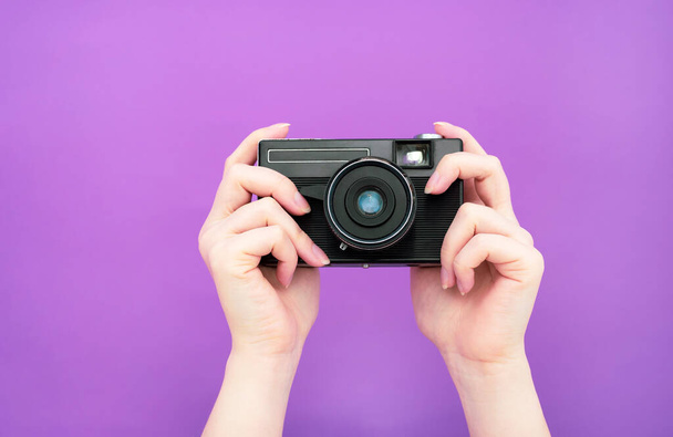 fekete kézi retro kamera kezében egy lila háttér. elkülöníteni. banner. - Fotó, kép