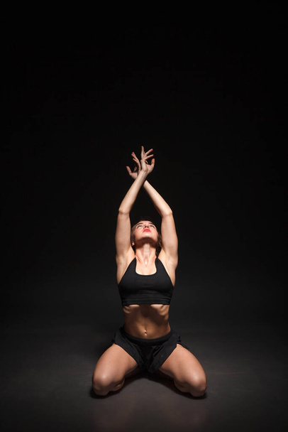Young girl doing yoga on a black background - Foto, imagen