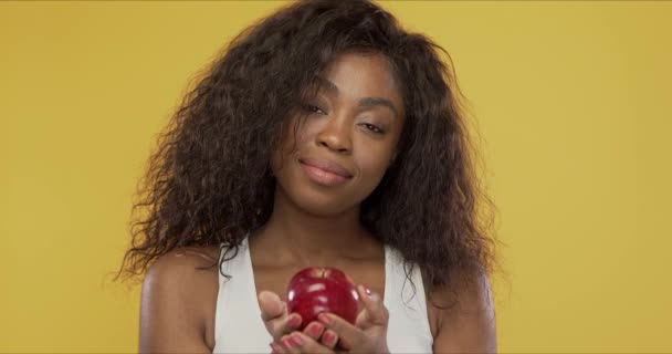 Positive ethnic female sharing apple with camera - Кадры, видео