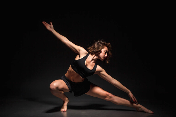 Young girl doing yoga on a black background - Valokuva, kuva
