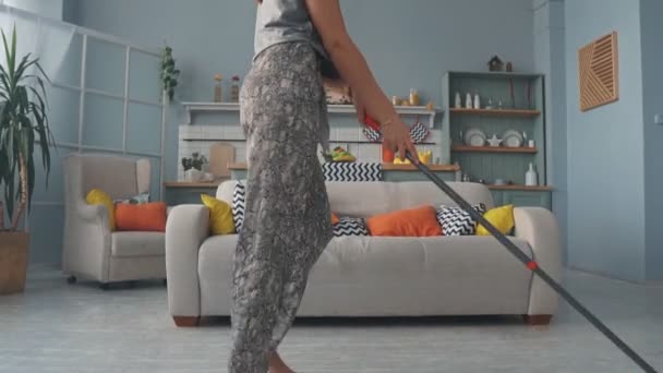 A young girl is having fun cleaning the house and dancing with a MOP - Video