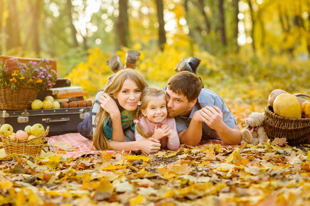 Papá, mamá e hija se divierten juntas durante un picnic de otoño en la calle
. - Foto, Imagen