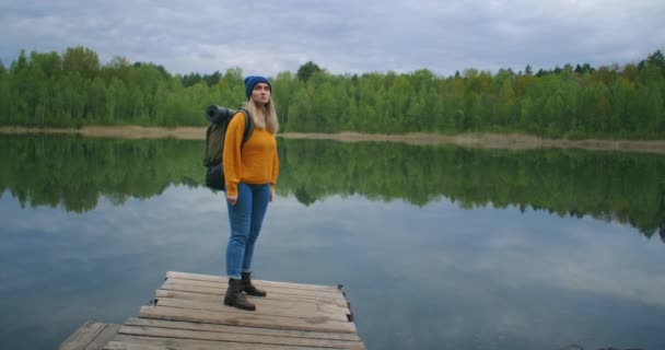 Viaggiatore donna caucasica sulla riva del famoso lago turistico nel bosco. Il concetto di viaggio e avventura nella foresta nella stagione autunnale ed estiva. La donna guarda le croci di un lago di foresta
 - Filmati, video