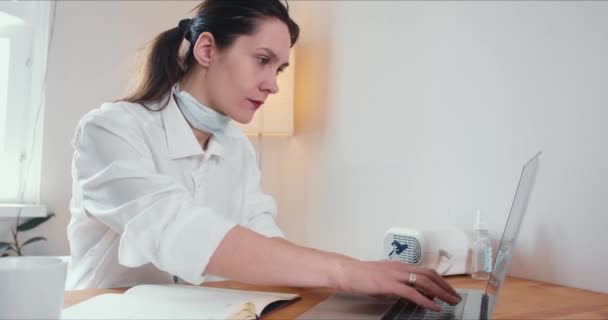 Hermosa mujer médica caucásica profesional feliz consultando a la gente en línea en la conferencia web desde casa usando el ordenador portátil
. - Metraje, vídeo